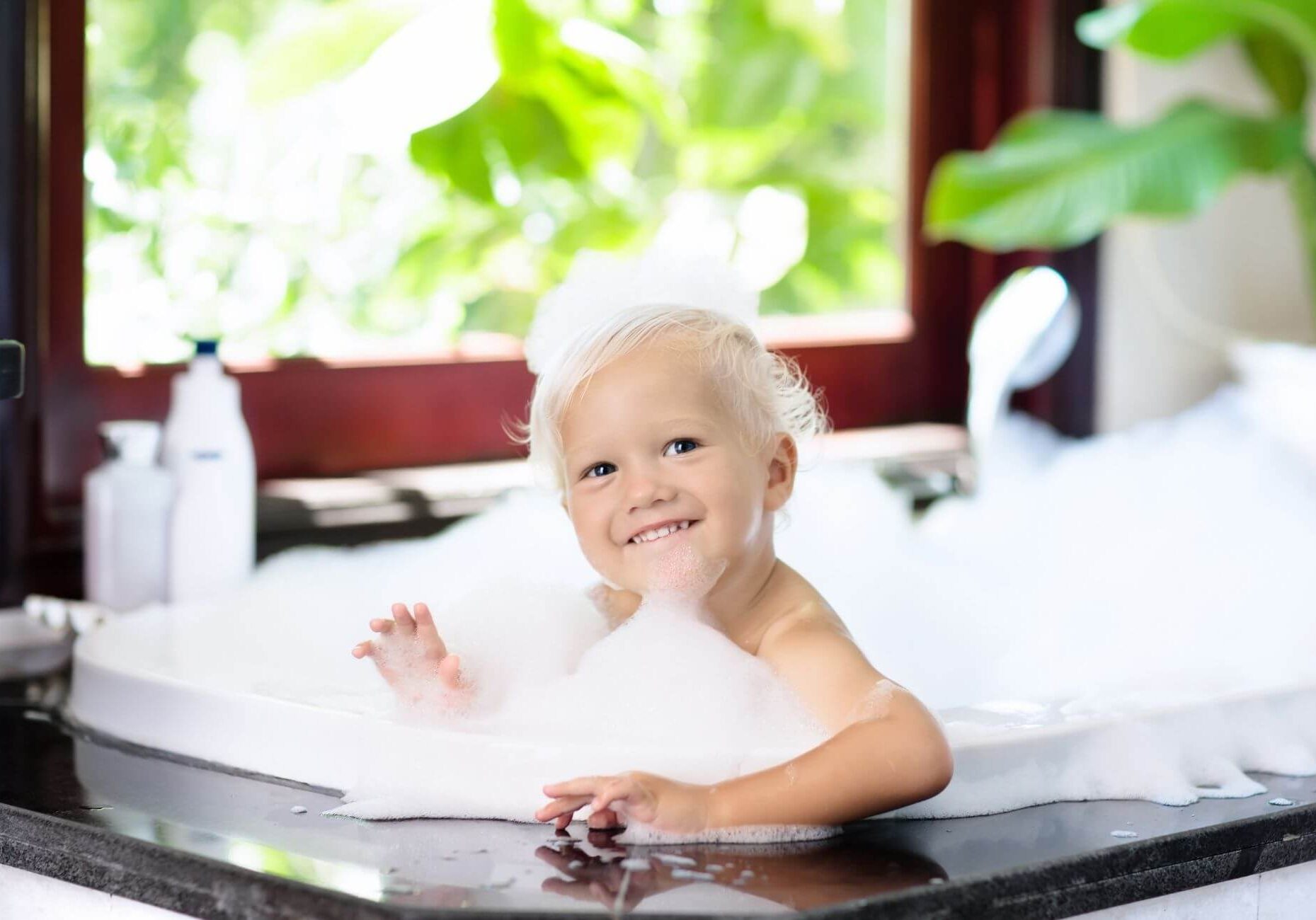 baby covered in soap bubbles in bathtub
