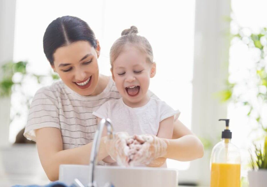 mother helping daughter wash hands